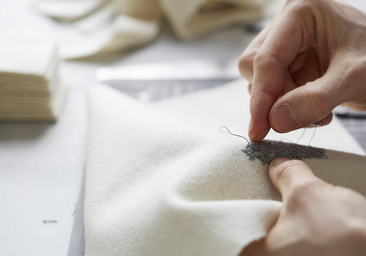 Person embroidering a white cloth 