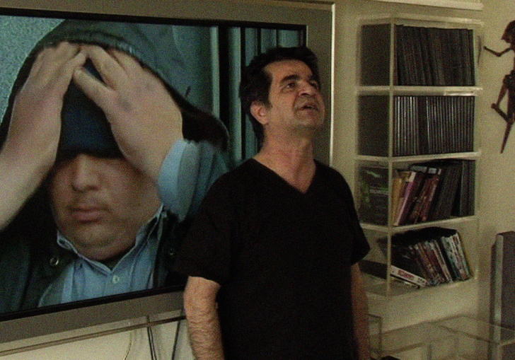 a man stands in a house with an image behind him, the image is of a man with his head in his hands