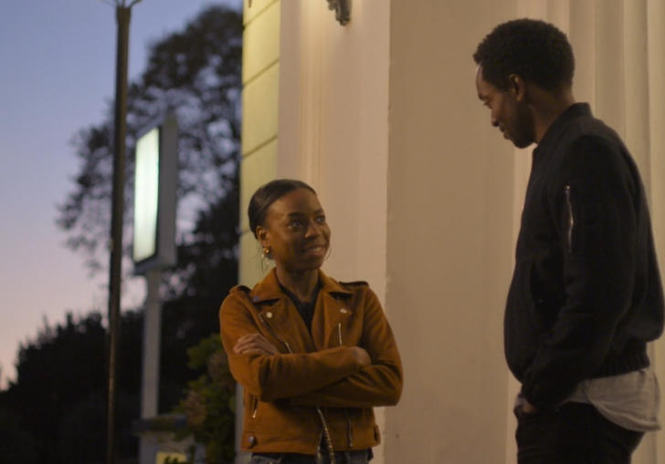two young people stand opposite each other talking at dusk