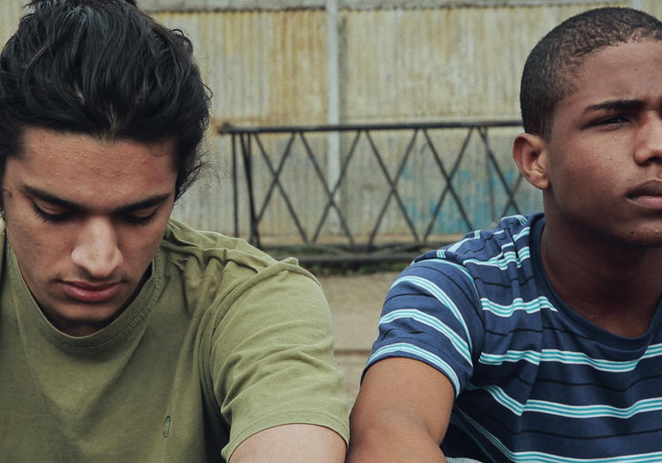 Two young men sitting next to each other on some steps