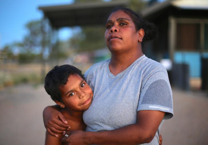 a mother and son stand embracing 