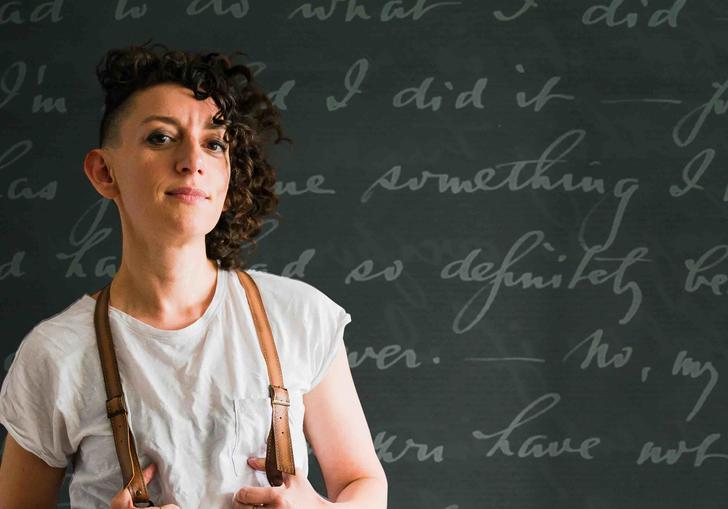 Person standing against a blackboard wearing braces. 