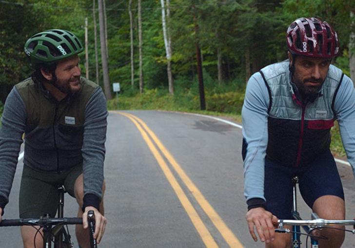 two men cycling on a road side by side