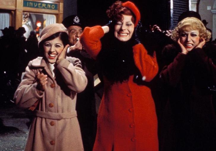 three women wearing big coats and giggling in the street