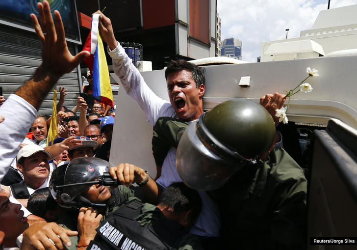 a protestor gets pushed into a police van whilst holding up a flag