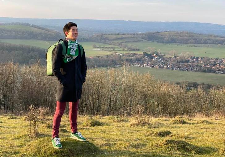 a young adult standing on top of a mountain