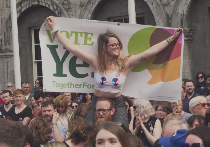 woman sits on the shoulders of a friend at a protest