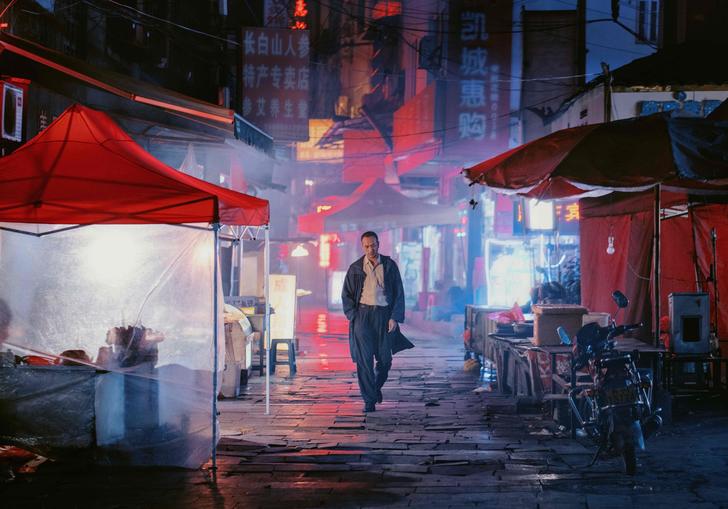 a man walks through the darkly lit streets of a city