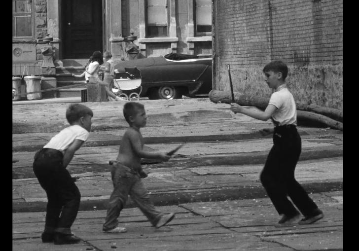 three boys play with sticks in the middle of the city