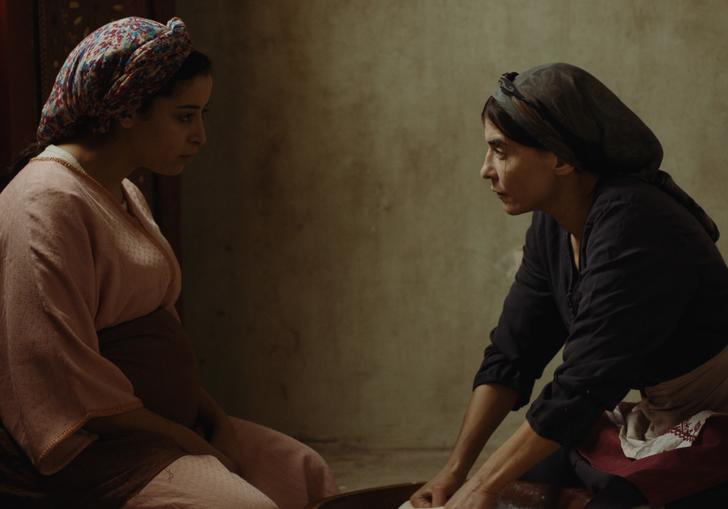 two woman sitting in a dark room look at each other