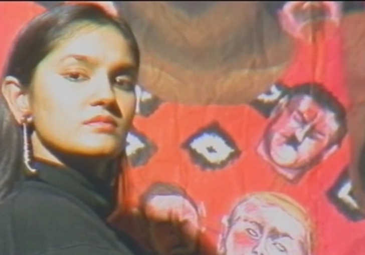 a woman looking into the camera against a colourful red background