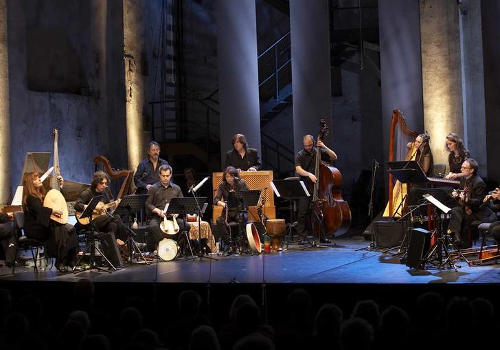 L'Arpeggiata on a lit stage, playing their period instruments