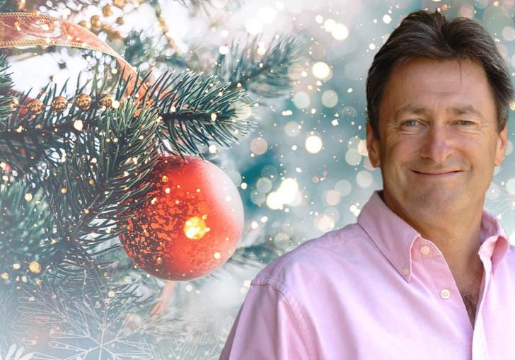 Alan Titchmarsh smiling, with a Christmas tree and bauble behind him