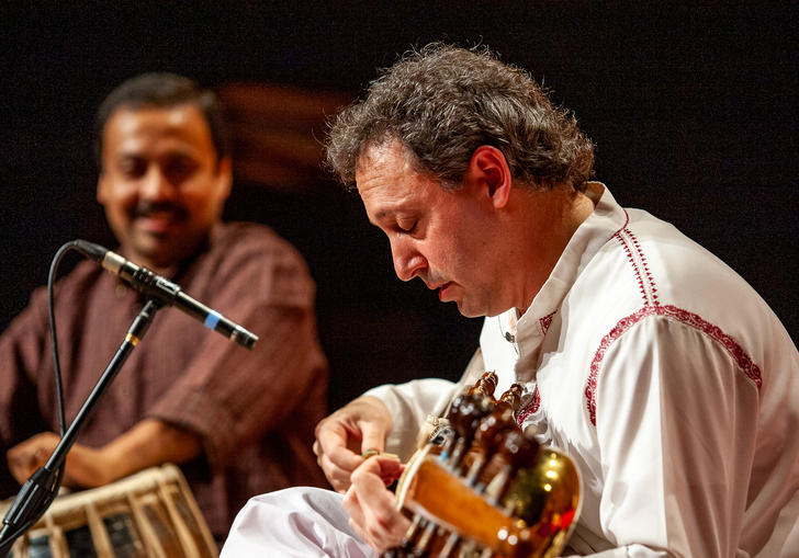 Ken Zuckerman playing the sarod with his head lowered