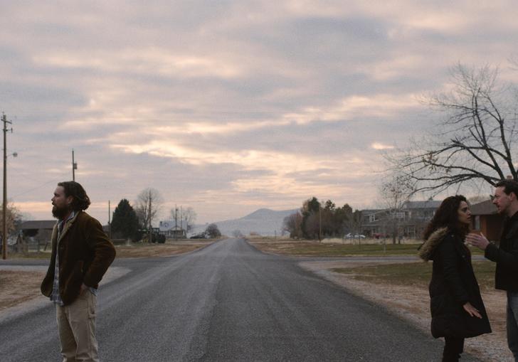 a couple stands at opposite sides of the road looking away from each other