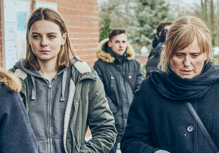 a girl and an older woman stand next to each other looking sad and distressed