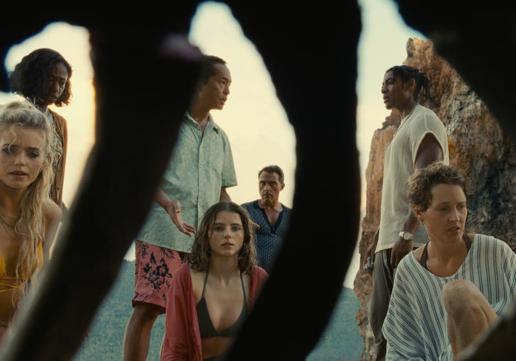 a group of people are on a beach with dark shapes between them