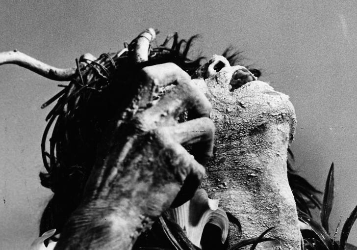 an image of a man covered in some kind of mud and headdress looking upwards 