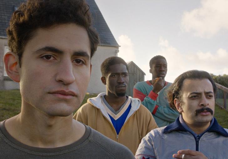 four refugees stand together outside of the house they're living in in Scotland