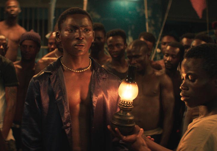a group of men stand in a circle and a boy in the middle holds a gas lamp