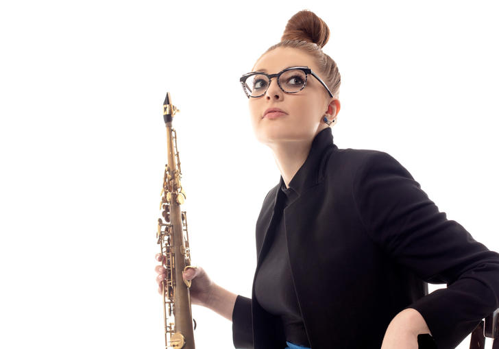 Jess Gillam sitting on a chair holding her saxophone 