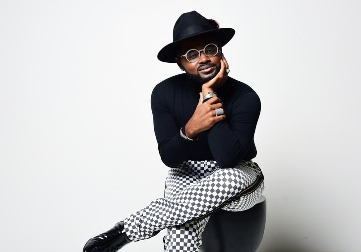 John Holiday smiling, sitting on a stool 