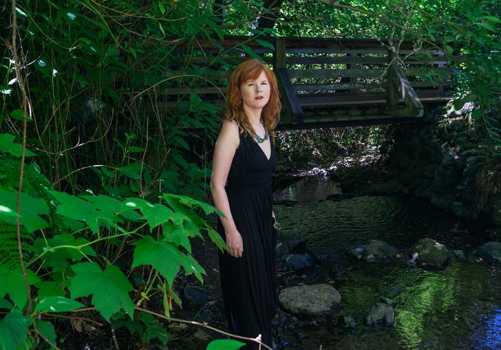 Sarah Cahill standing in a garden in front of a bridge