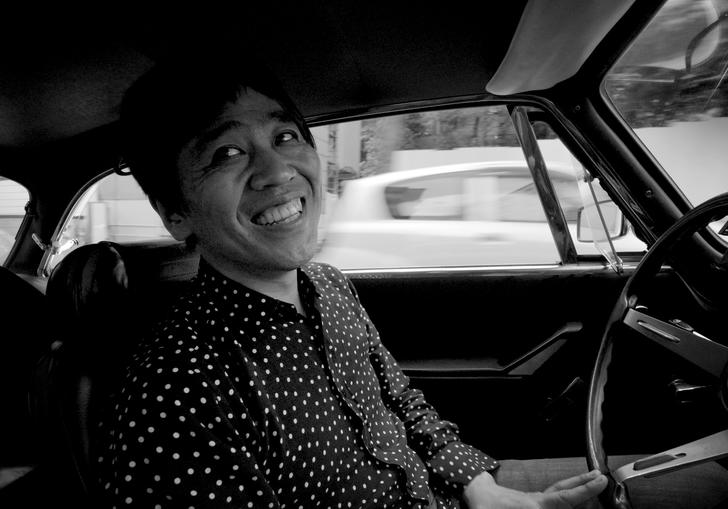 Architect Ryue Nishizawa inside his vintage Alfa Romeo car in a black and white still image 