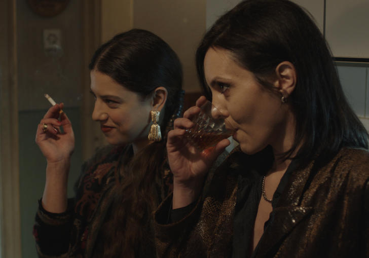 Two women dressed in brown drink liquor in the kitchen in a still from the film Celts (2021)
