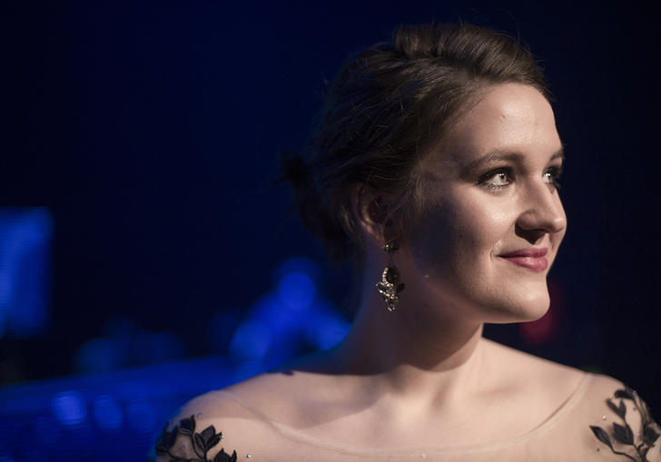 Lise Davidsen looking to her left, smiling, in front of a blue-lit backdrop