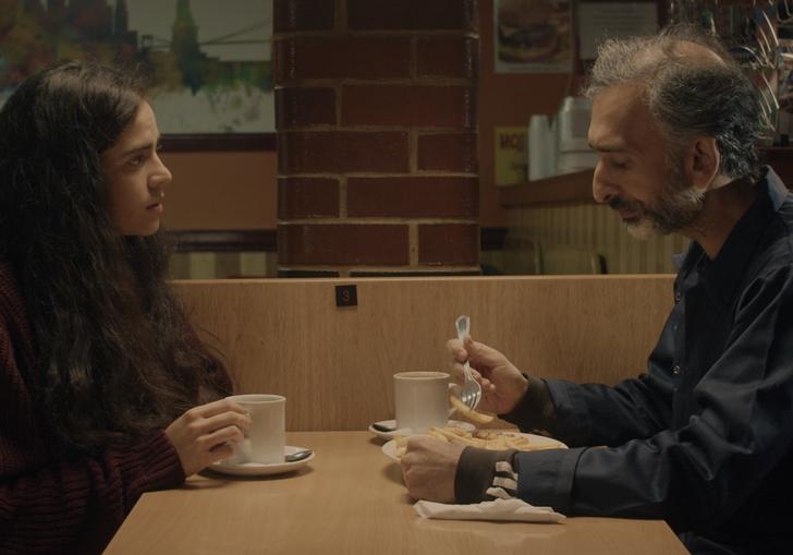 A photographic still of a young woman and an older man having a coffee from Without Warning