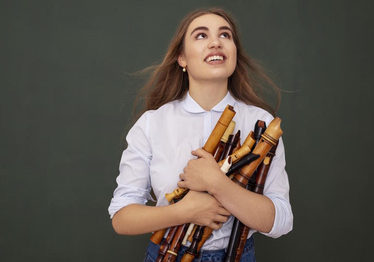 Lucie Horsch stands in the centre of the image, looking up and holding a big bundle of recorders in her arms