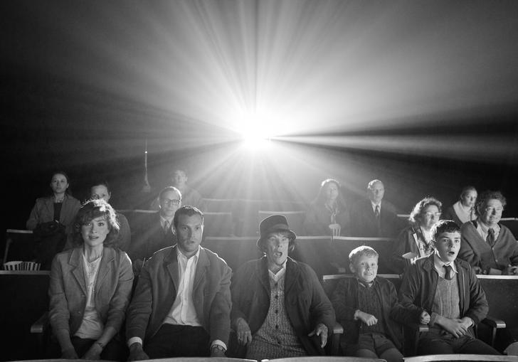 Black and white image of the family from Belfast, seated watching a film
