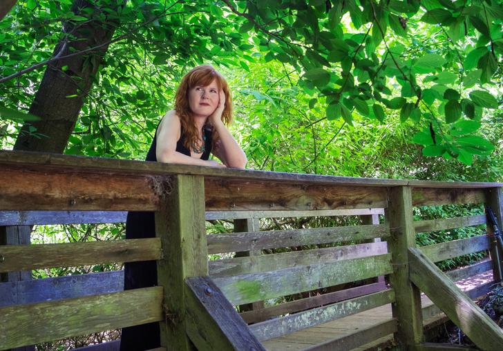 Sarah Cahill standing on a wooden bridge surrounded by trees