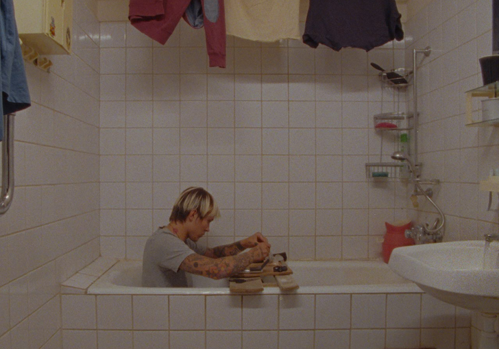 A still of a man sitting clothed in a bath, from Detours