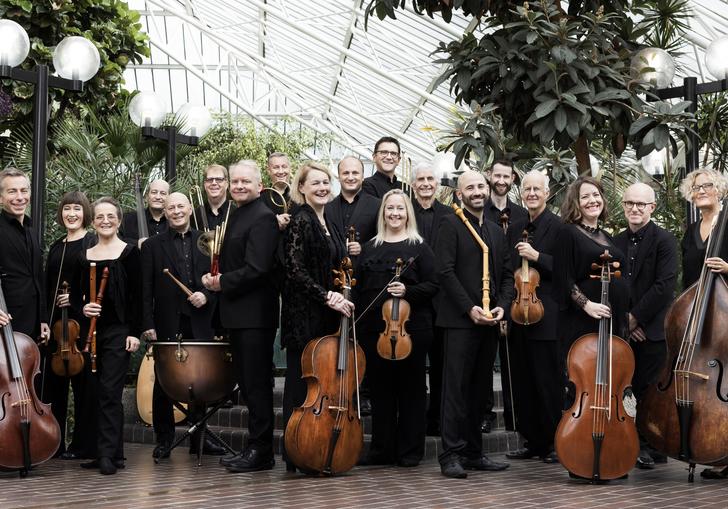 Players of the Academy of Ancient Music standing with their instruments in the Barbican Conservatory