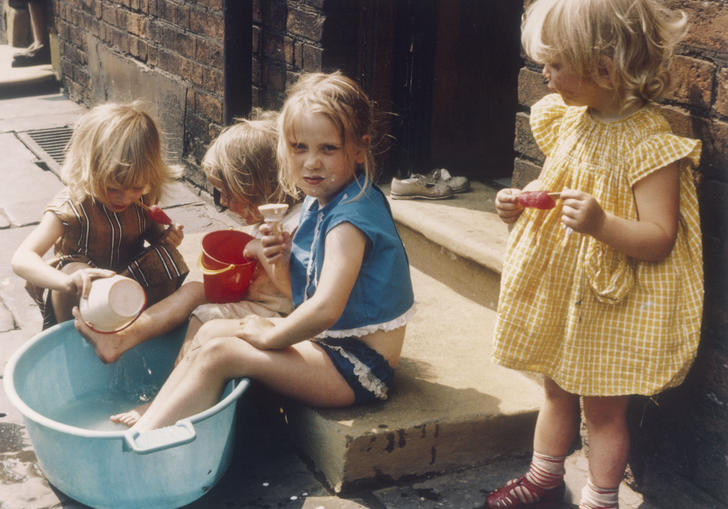 a photograph of some young girls eating ice creams and playing in a bucket of water 
