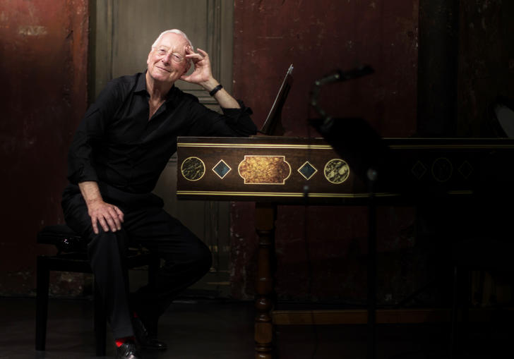 William Christie sitting at a harpsichord smiling