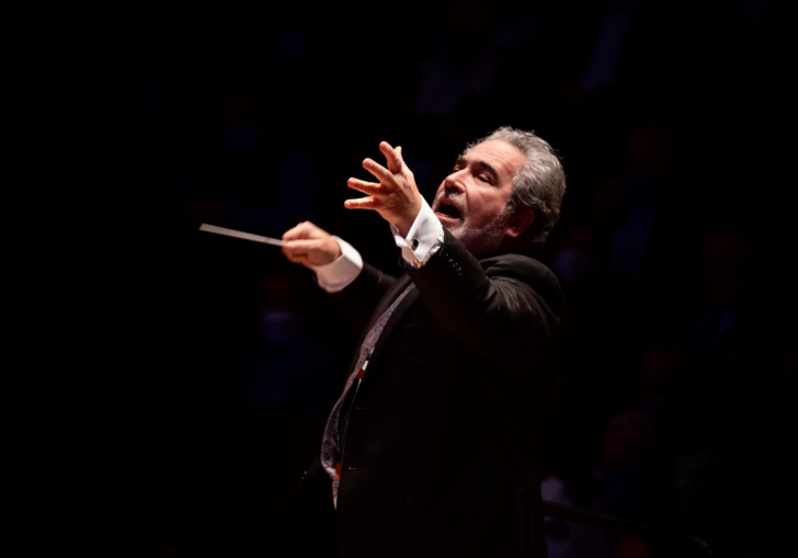 A spotlight shines on Carlo Rizzi as he conducts