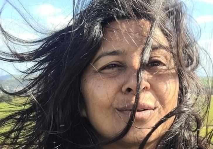 Davel Holvek Patel standing in a field, her hair is being blown by the wind