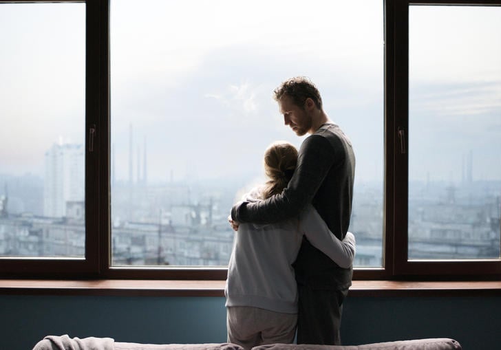 A father and daughter hug at a window in Reflection