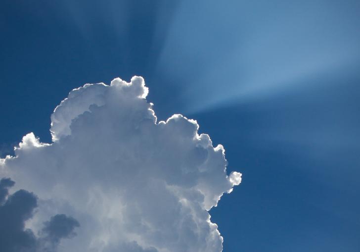 Photo of the sun's rays shining from behind a cloud