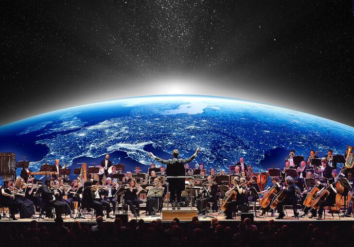 The London Concert Orchestra playing in front of an image of the Earth as seen from space