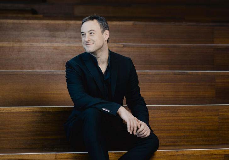 Jonathan Cohen sitting on wooden steps