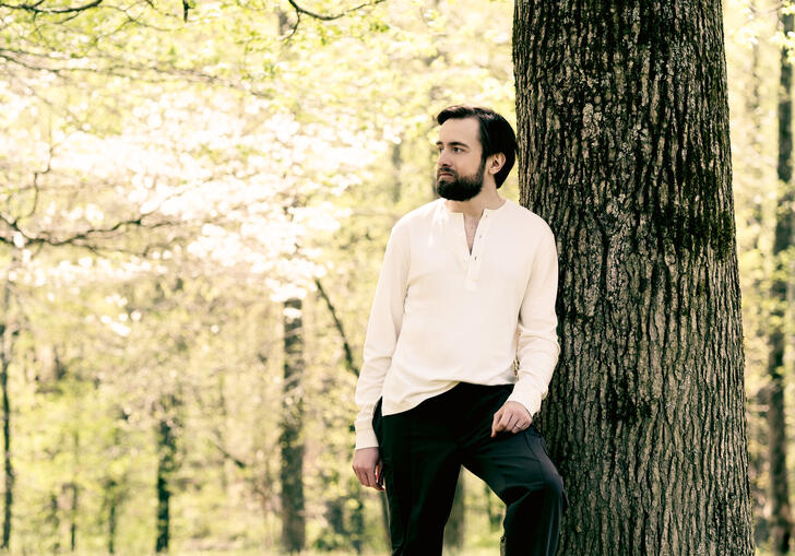 Daniil Trifonov standing next to a tree trunk