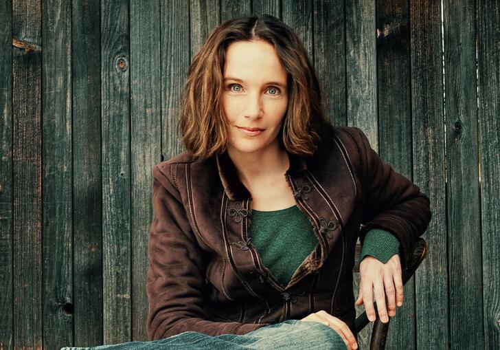 Hélène Grimaud sitting on a chair in front of a wooden fence