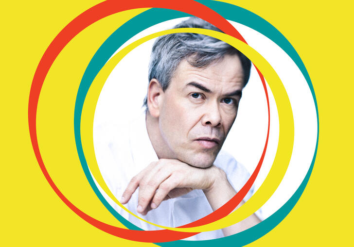 Hannu Lintu leans on his hand. Yellow BBC SO branding surrounds his centralised image