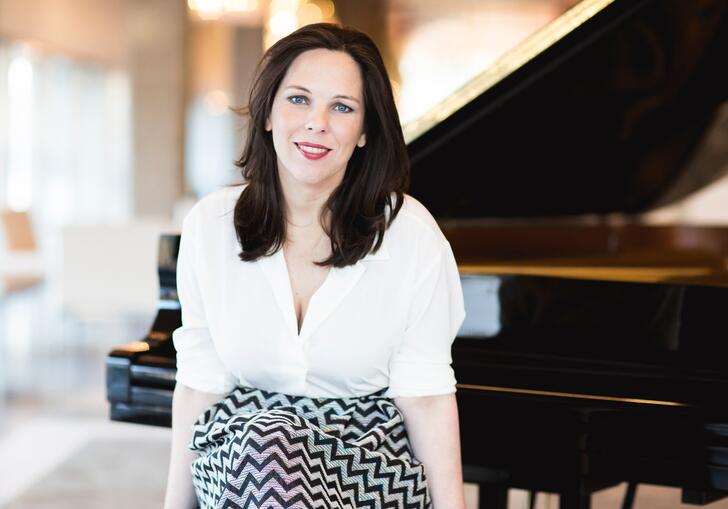 Daria van der Bercken sits on a piano stool, in front of an open grand piano