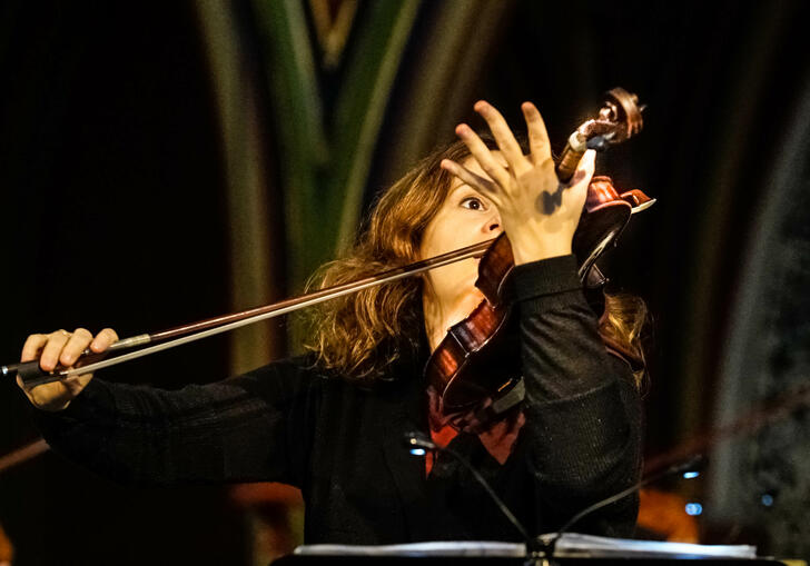 Patricia Kopatchinskaja plays her violin - it's held in front of the right hand side of her face 