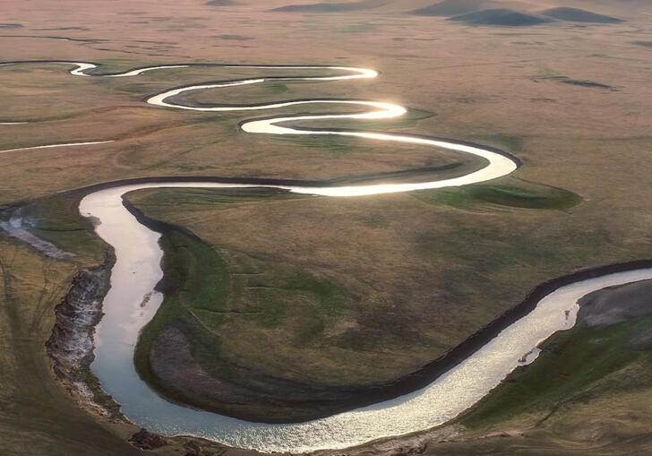 Still image from River, showing a drone shot of a large meandering river